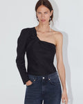Woman wearing a black one-shoulder top and blue jeans against a white background
