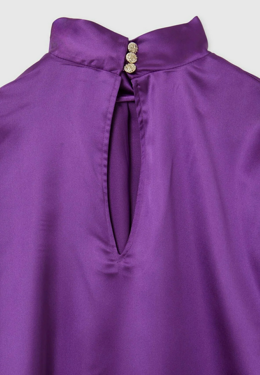 Close-up of a purple blouse with a button detail on a light gray background