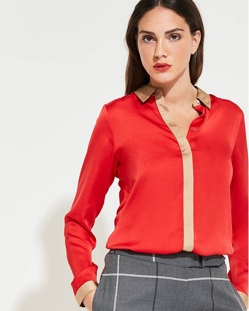 Woman wearing a red blouse with a beige collar and gray checkered pants on a white background