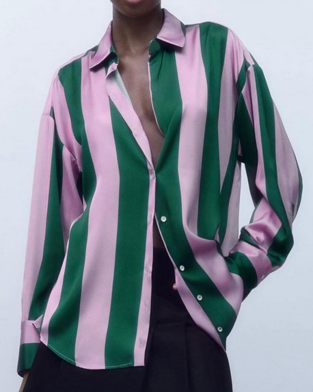 Green and pink striped shirt worn by a person on a plain background