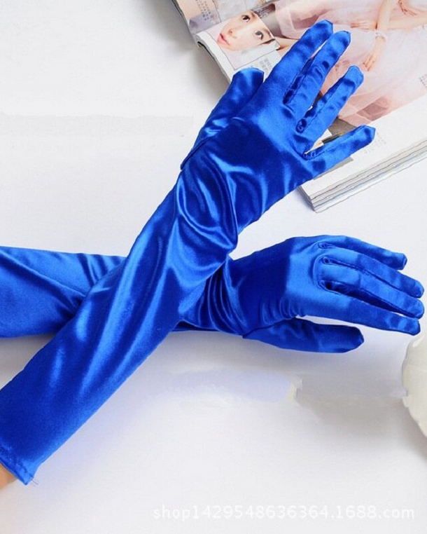 Blue satin gloves on a white surface with a magazine in the background