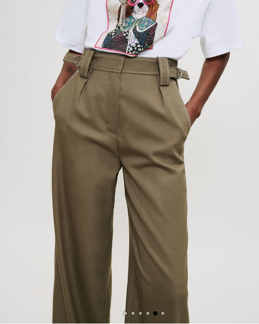 Person wearing a white t-shirt with a graphic design and beige pants on a plain background