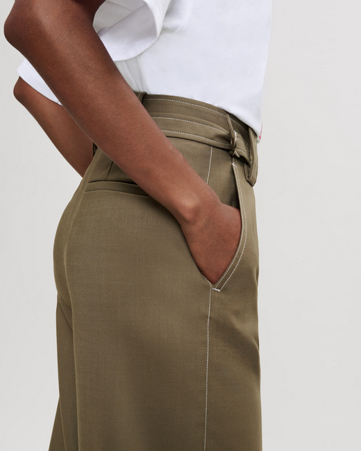 Person wearing olive green pants and a white shirt on a plain background