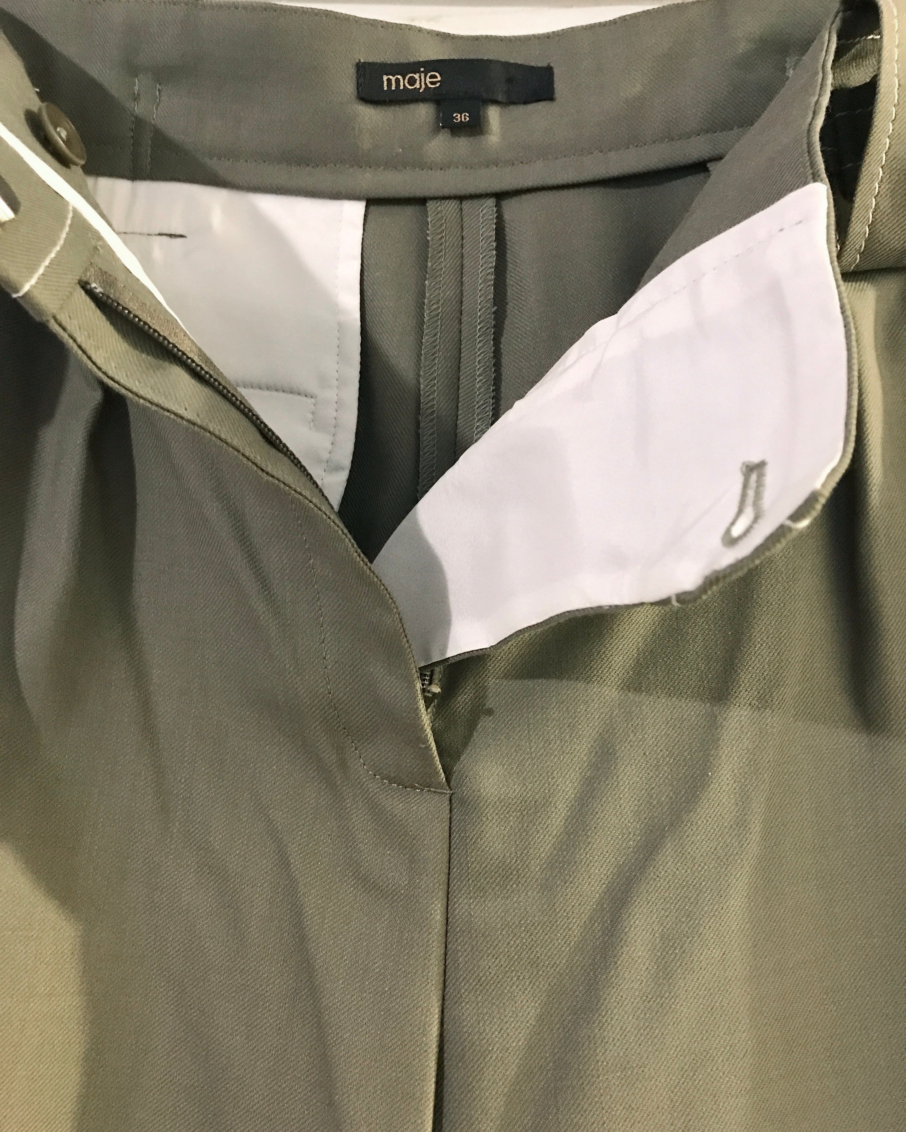 Close-up of a green jacket with a white lining and 'maje' label.