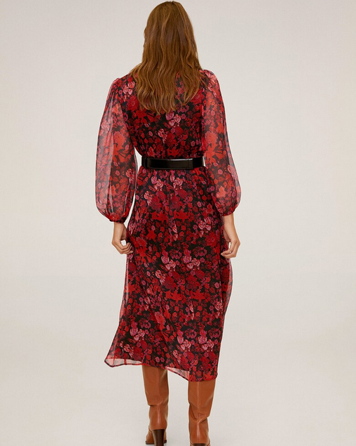 Woman wearing a red floral dress with sheer sleeves on a white background
