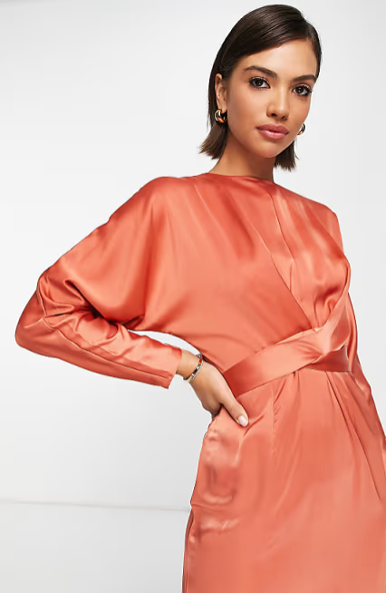 Woman wearing a coral satin dress against a white background