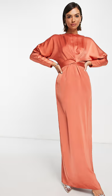 Woman wearing a coral long-sleeve gown on a white background