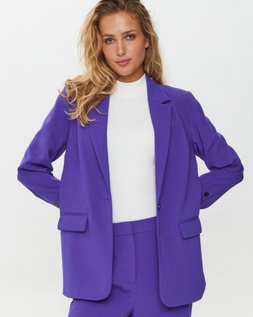 Woman wearing a purple suit with a white top on a white background