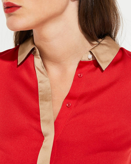 Close-up of a red shirt with beige collar and cuffs worn by a person.