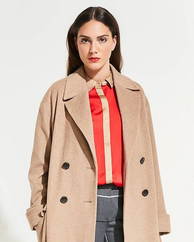 Woman wearing a beige trench coat over a red shirt and plaid skirt on a white background