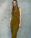 Woman wearing a sleeveless green dress against a gray background
