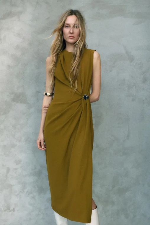 Woman wearing a mustard yellow dress against a gray background