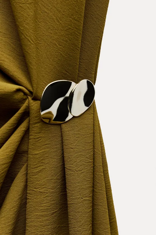 Black and white circular brooch on a green fabric background