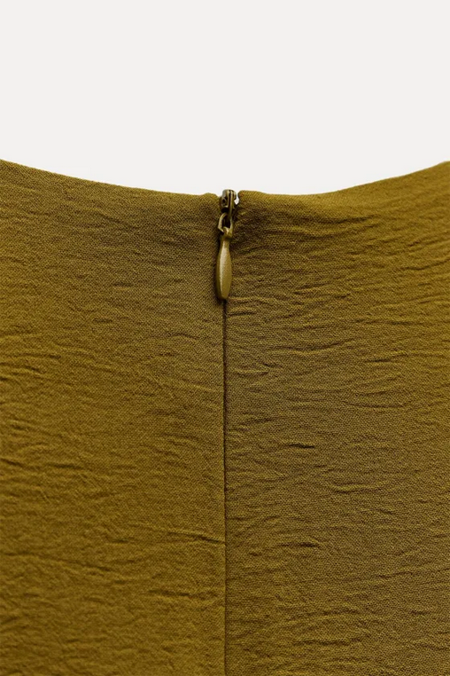 Close-up of a mustard yellow fabric with a zipper on a white background